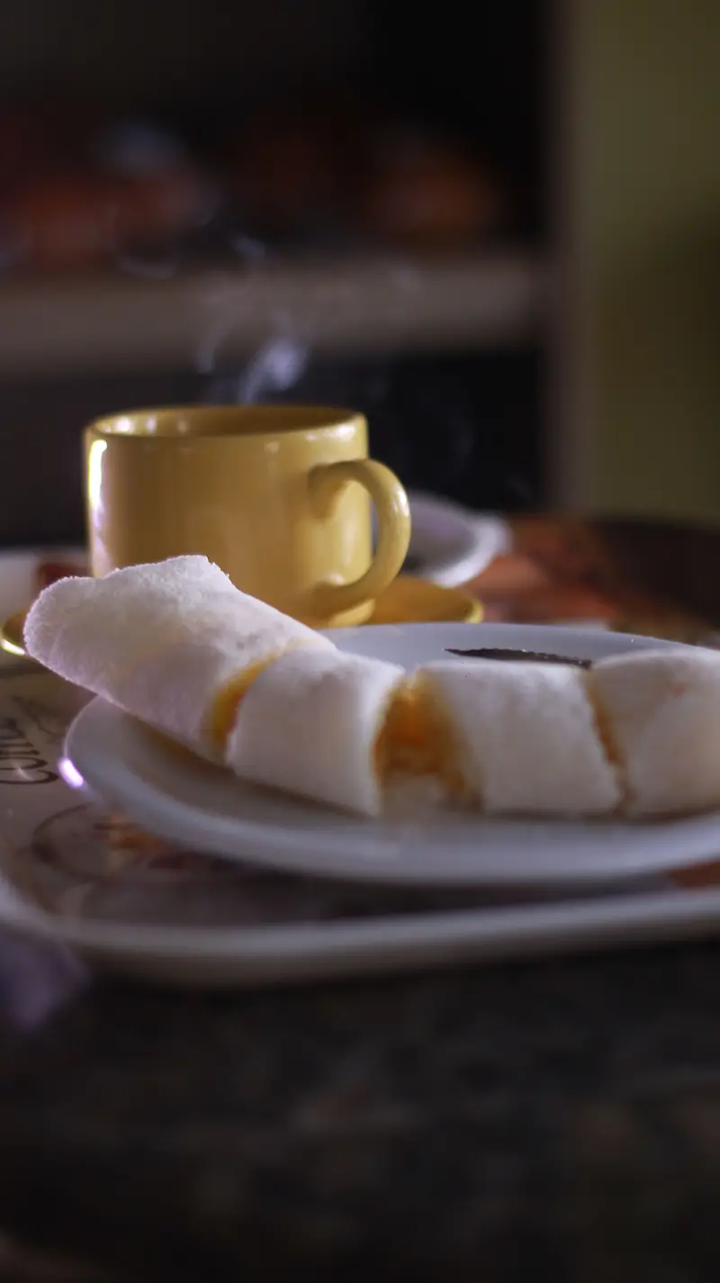 Caneca amarela de café ao lado de um prato com tapioca