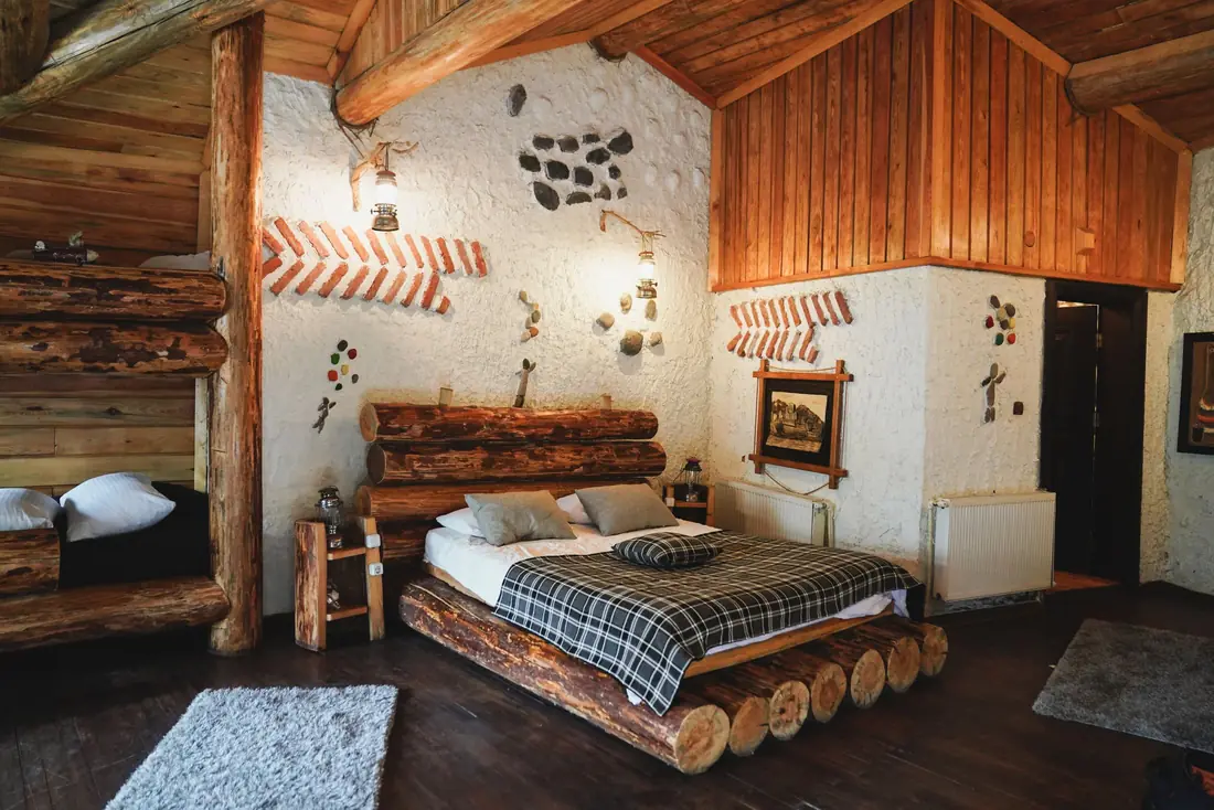 Quarto rústico com cama de troncos e paredes de pedra caiada
