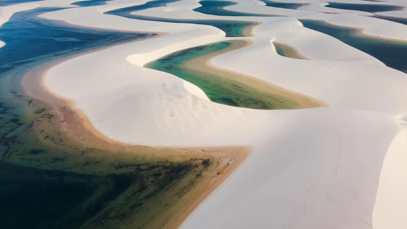 Vista do alto de dunas brancas recortadas por lagoas verdes e azuis